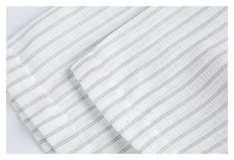 Close-up of white fabric with fine gray stripes and a folded seam or pocket edge.