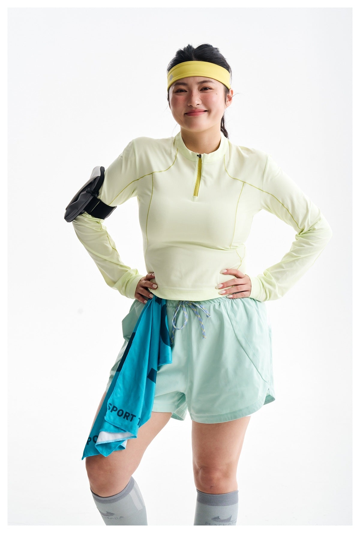 Model wearing a pale yellow quarter-zip top with contrasting seam lines and mint shorts, shown from the front.