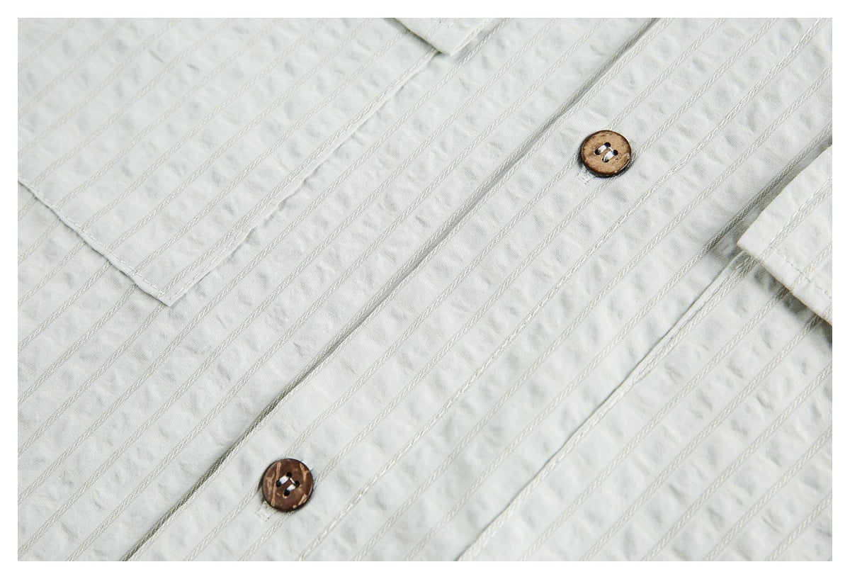 Close-up of a white shirt's textured vertical stripes and two brown buttons.