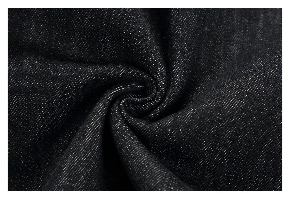 Close-up of black fabric with a fine, lightly speckled weave gathered into soft folds.