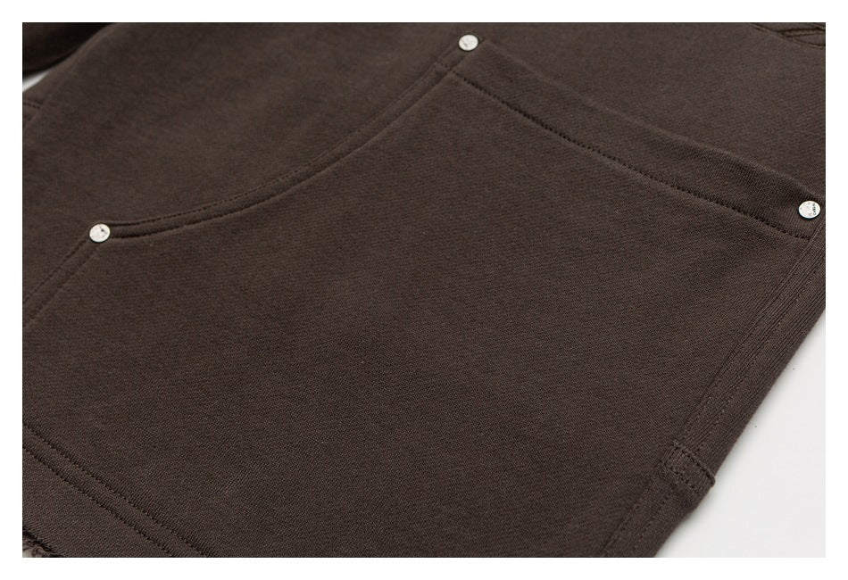 Close-up of dark brown sweatpants with a large pocket and small round metal buttons.