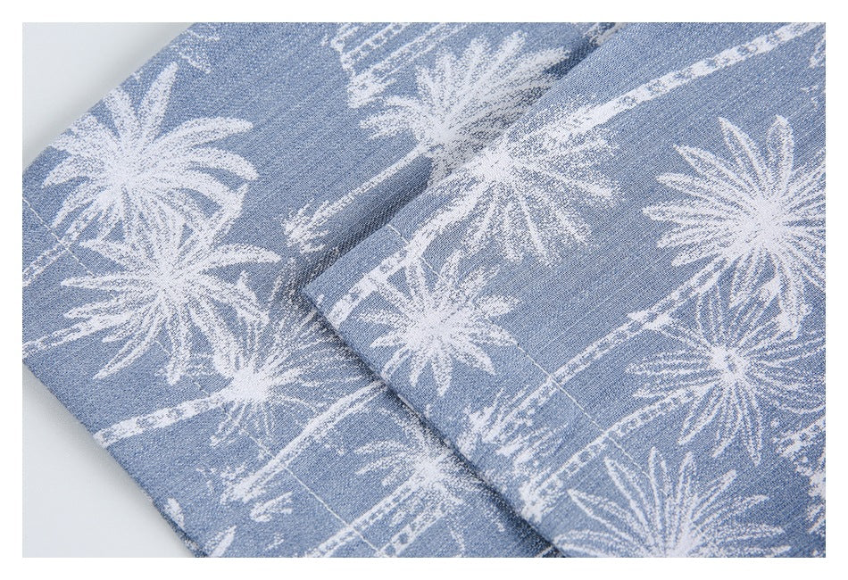 Close-up of a folded edge and stitching on light blue fabric with a white palm-tree print.