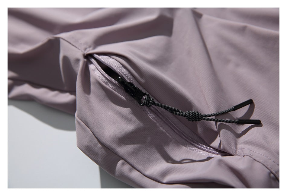 Close-up of a zippered pocket on the mauve shirt, with a dark cord pull.
