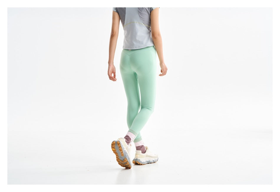 Cropped rear view highlighting mint leggings with a light gray top and striped socks.