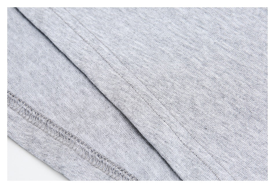 Close-up of light heather gray knit fabric with a double-stitched seam and overlocked edge.