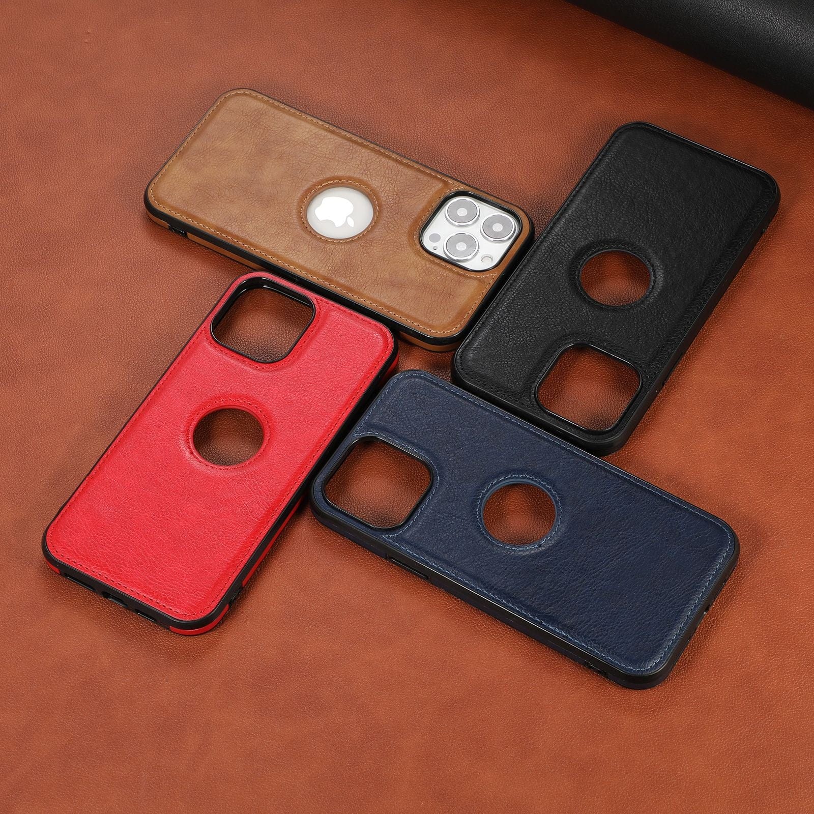 Four iPhone 16 Pro Max cases made from premium synthetic leather, available in brown, black, red, and blue colors, encircle a smartphone on a brown leather surface. The phone's camera and Apple logo are visible through the brown case.