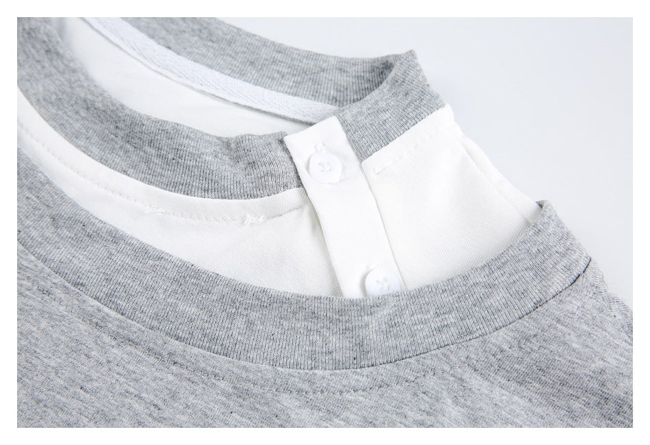 Close-up of the layered neckline and white two-button placket beneath the gray crew neck.