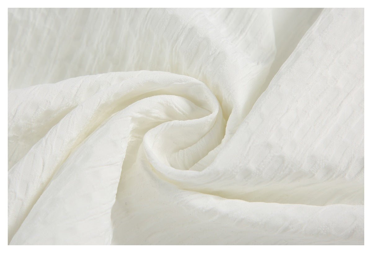 Close-up of softly draped white fabric showing its folds and textured surface.