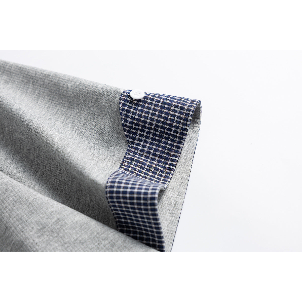 Close-up of a heather-gray sleeve cuff turned back to show navy-and-white checked lining and a white button.