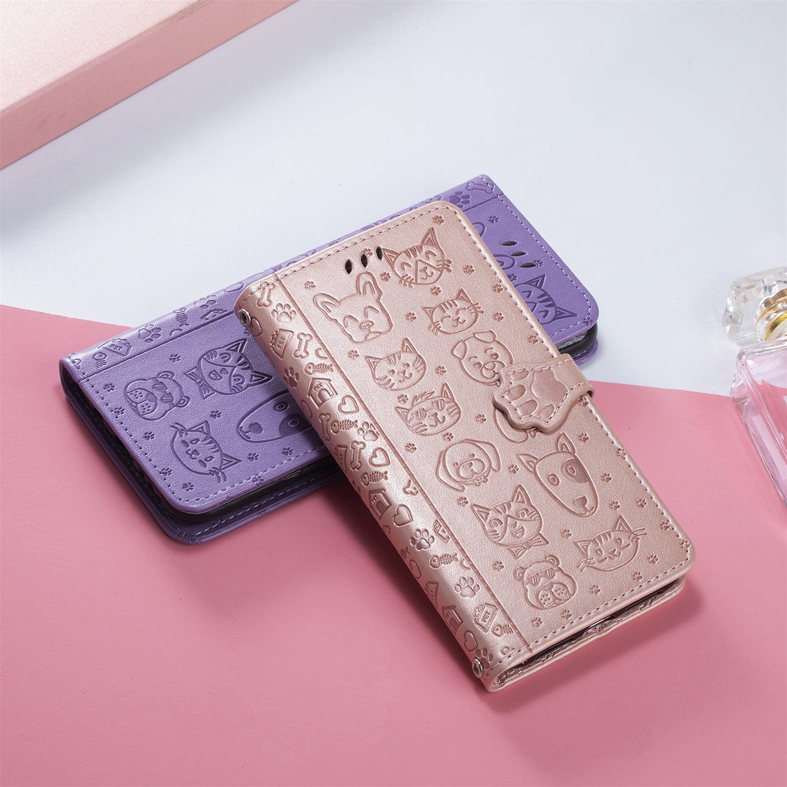 Two iPhone 16 Pro Max Wallet Cases, one in metallic pink and one in purple, showcasing a charming cat and dog embossed design with a PU leather finish, are elegantly placed on a pink and white surface. These stylish cases combine artistry with practicality, featuring card slots and a stand for added convenience.