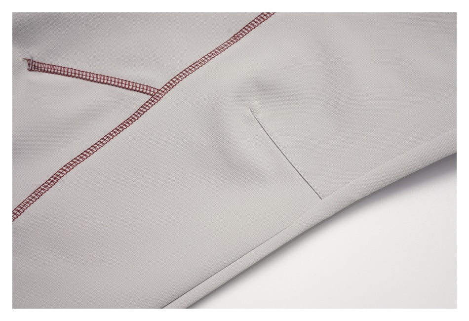 Close-up of light gray shorts showing burgundy overlock stitching and a finished hem.
