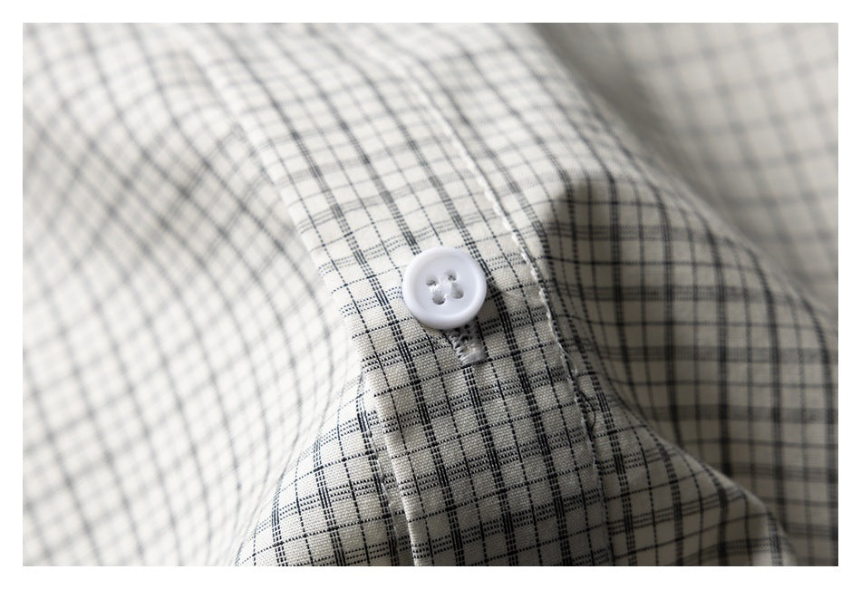 Close-up of a white button on cream fabric with a fine black windowpane check.