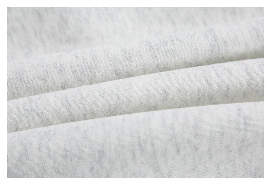 Macro view of light gray heathered fabric with parallel folded edges.