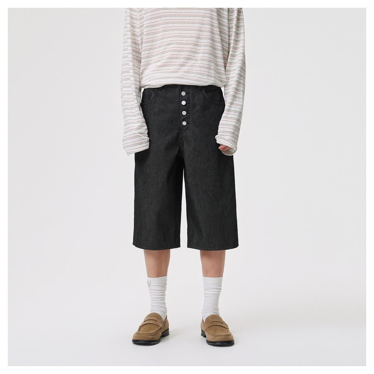 Model wearing black knee-length button-front shorts with striped long-sleeve top, white socks and tan loafers, front view