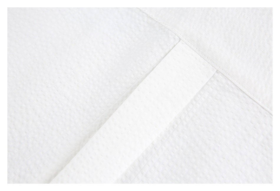 Close-up of a stitched white shirt placket against textured fabric.
