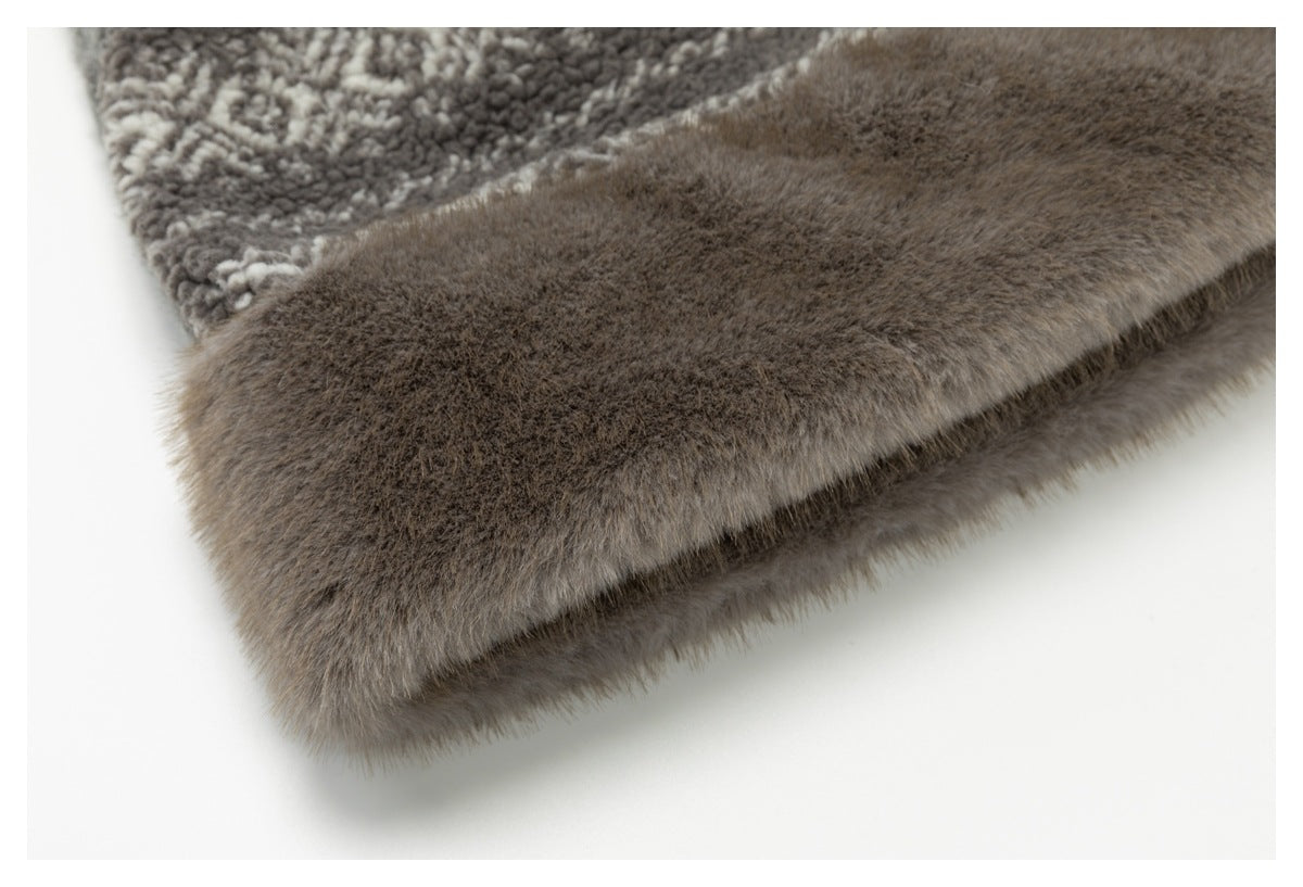 Close-up of a soft brown fur-like edge beside gray patterned fabric.