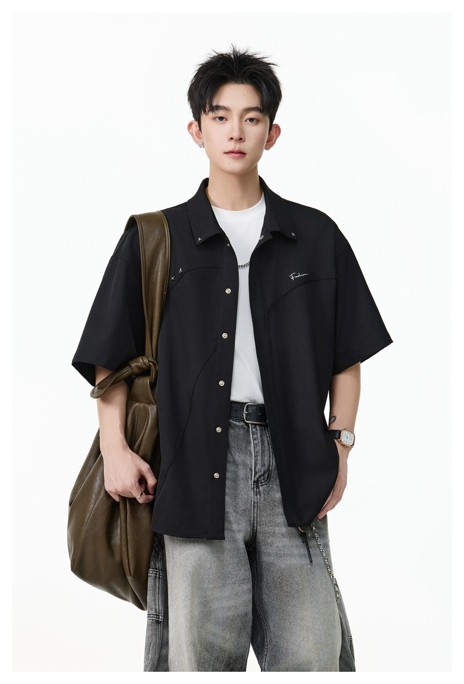 Closer view of a model wearing a black short-sleeve button-up shirt with silver buttons and chest details.
