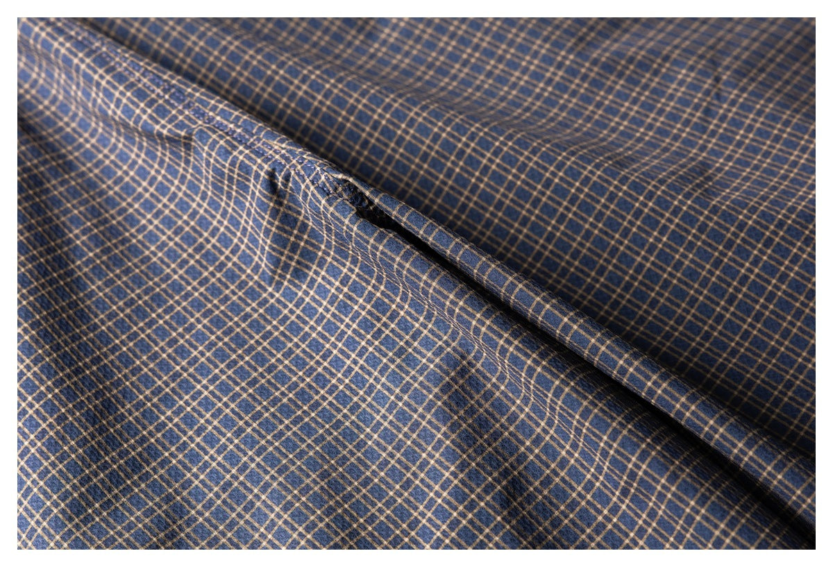 Close-up of navy fabric with a tan windowpane plaid pattern, draped to show its texture.
