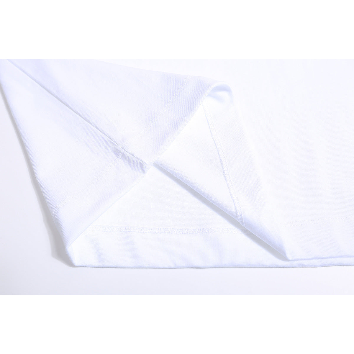 Close-up of a white T-shirt's sleeve, folded fabric, and stitched hem.