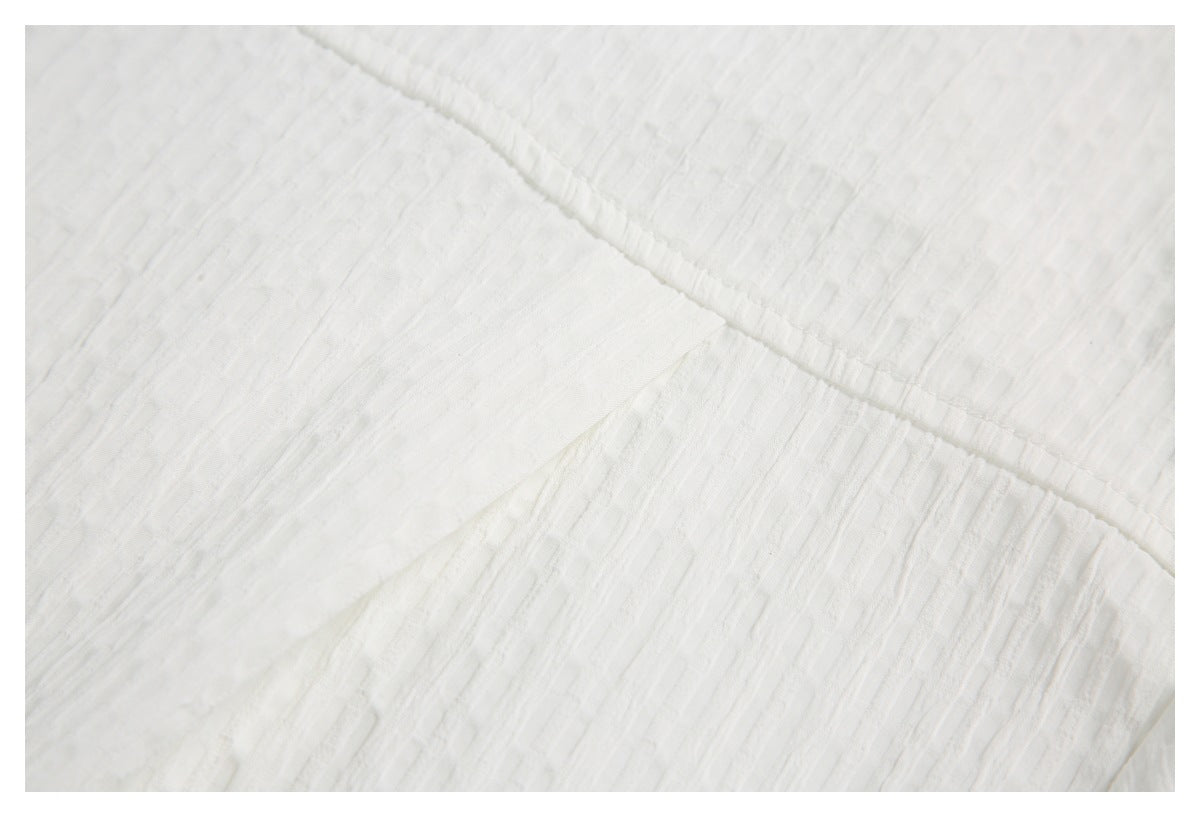 Close-up of white textured fabric with a diagonal stitched seam.