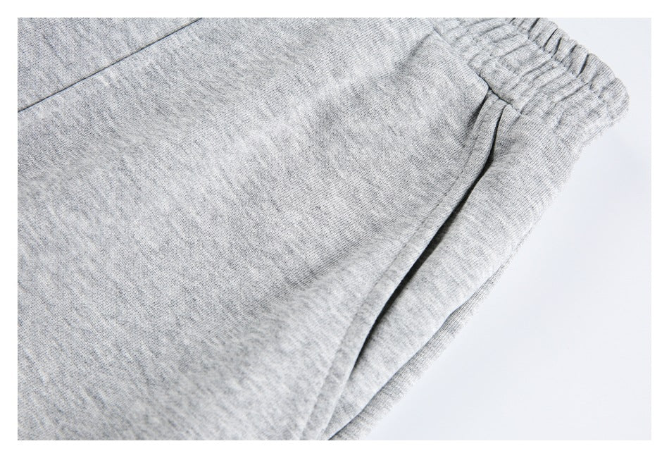 Close-up of light-gray shorts showing the heathered surface, elastic waistband and stitched seam.