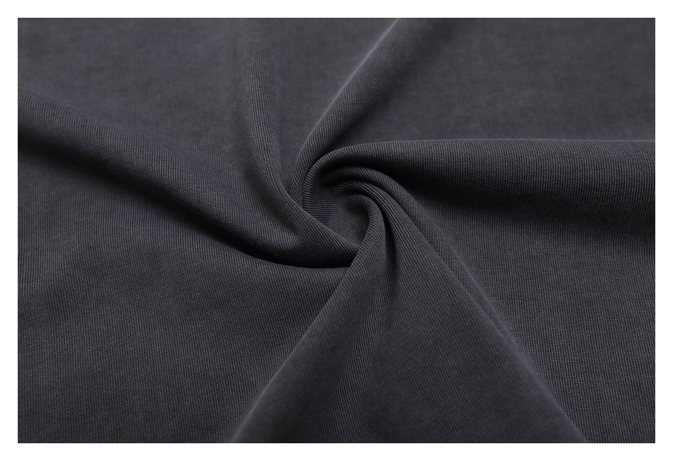 Close-up of dark charcoal fabric gathered into a swirl, showing a fine, subtle texture.