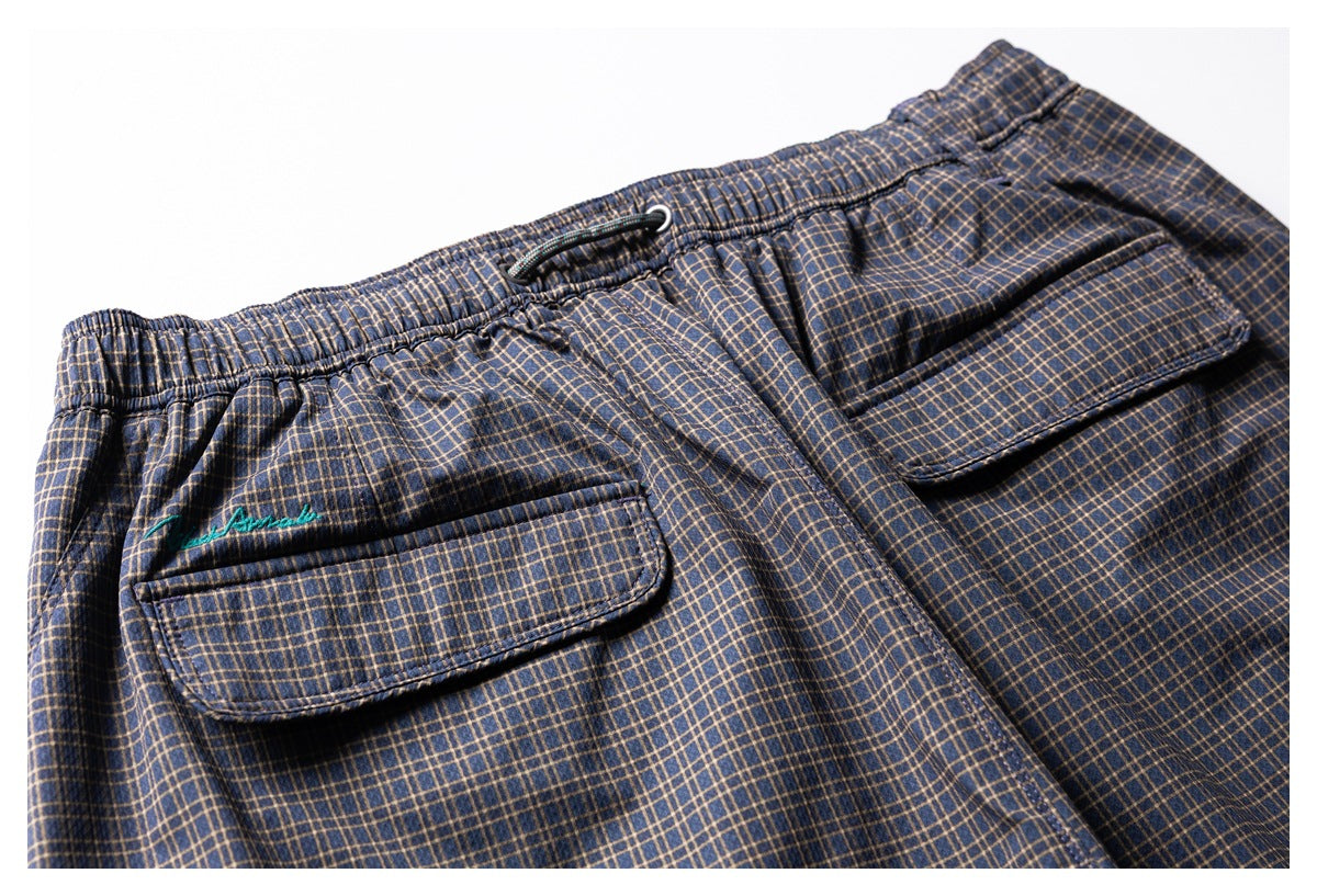 Close view of the back of navy plaid shorts with an elastic waistband, drawcord, and flap pockets.