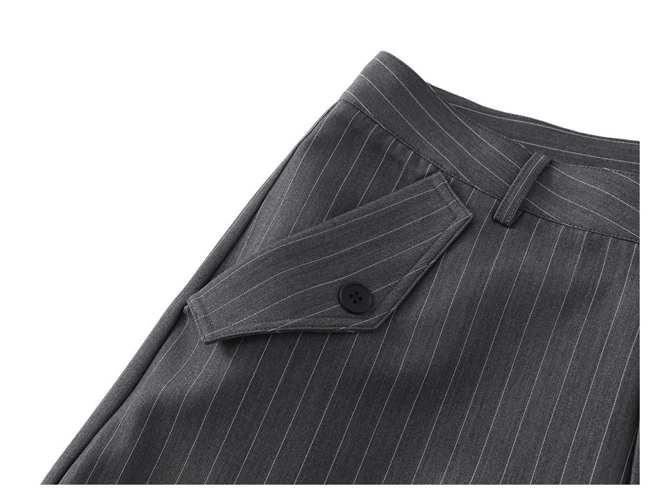 Close-up of charcoal gray pinstripe trousers showing a buttoned flap pocket and waistband.