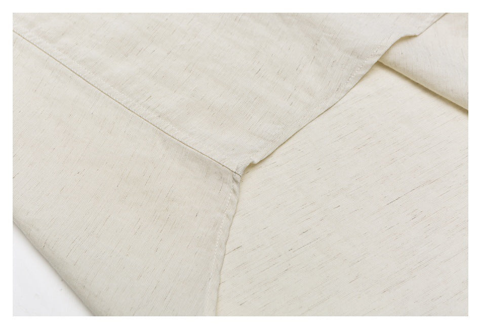 Close-up of stitched panel seams meeting on the off-white shirt.