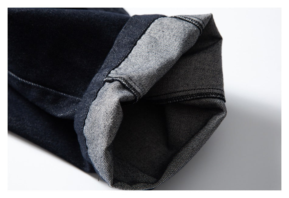 Close-up of a turned-up dark indigo pant hem, showing the lighter reverse side and stitching.