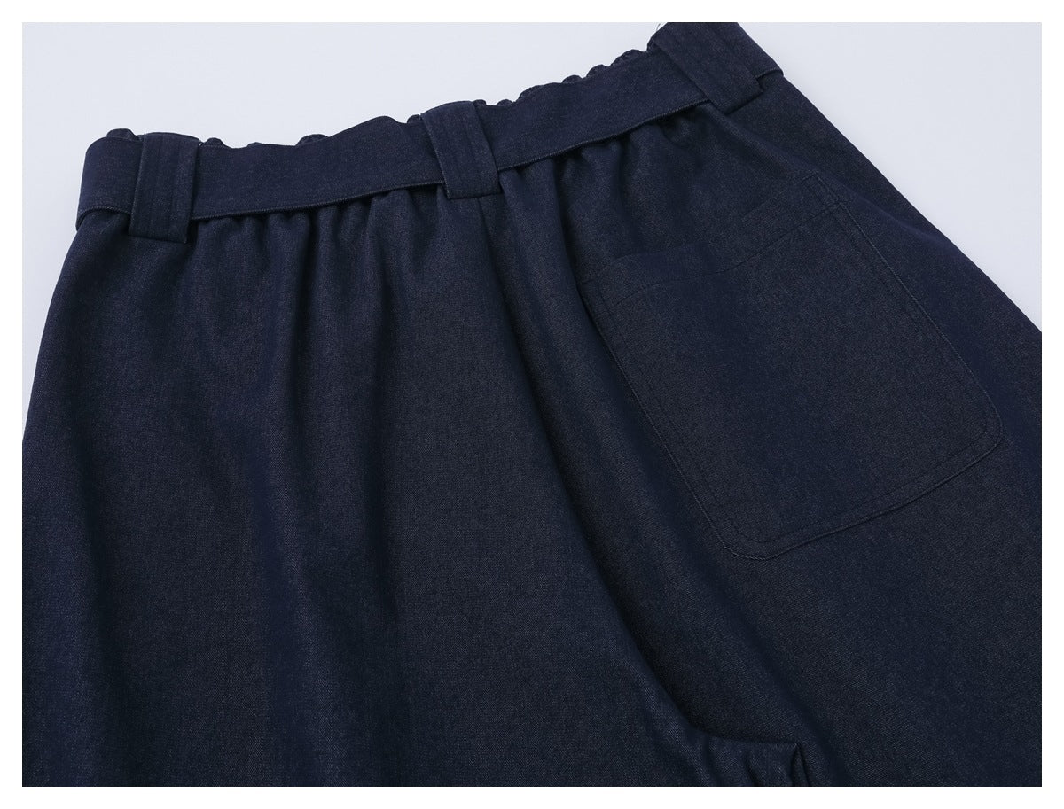 Close-up of dark navy trousers showing the gathered waistband, belt loops and a large patch pocket.
