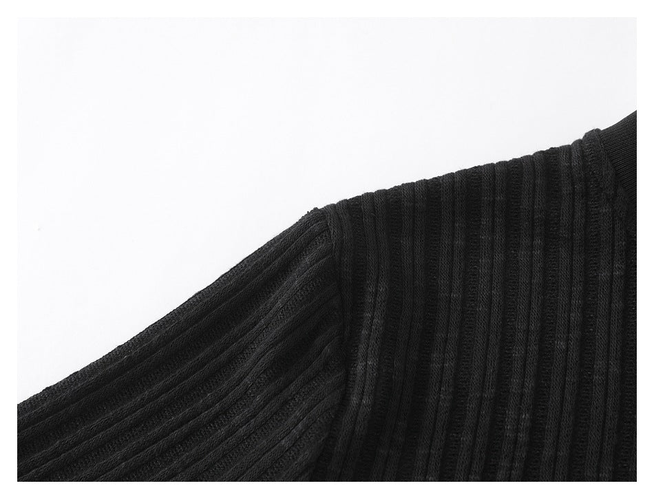Close-up of a black ribbed garment at the shoulder and sleeve seam.