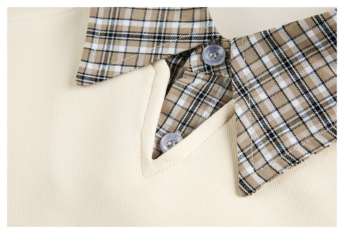 Close-up of a cream garment's plaid collar, neckline, and two translucent buttons.