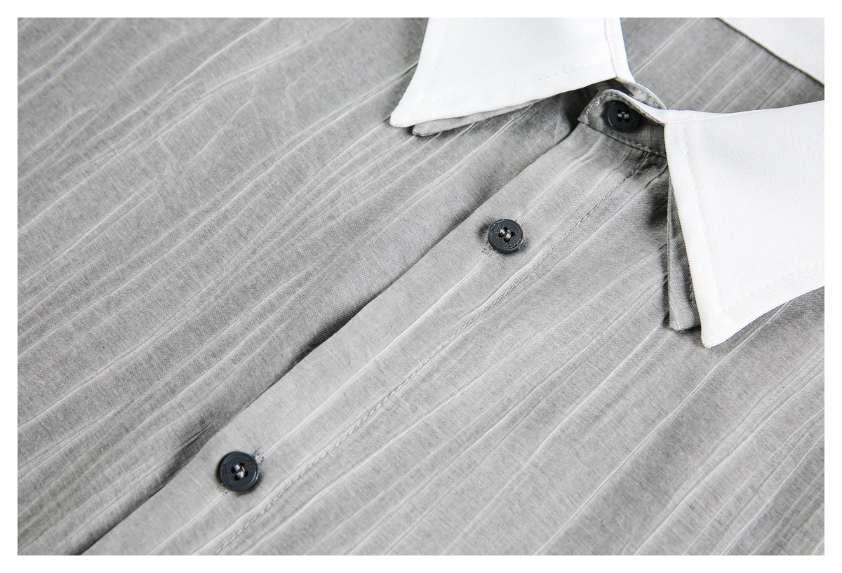 Gray shirt close-up showing its white collar, dark buttons, and stitched front placket.