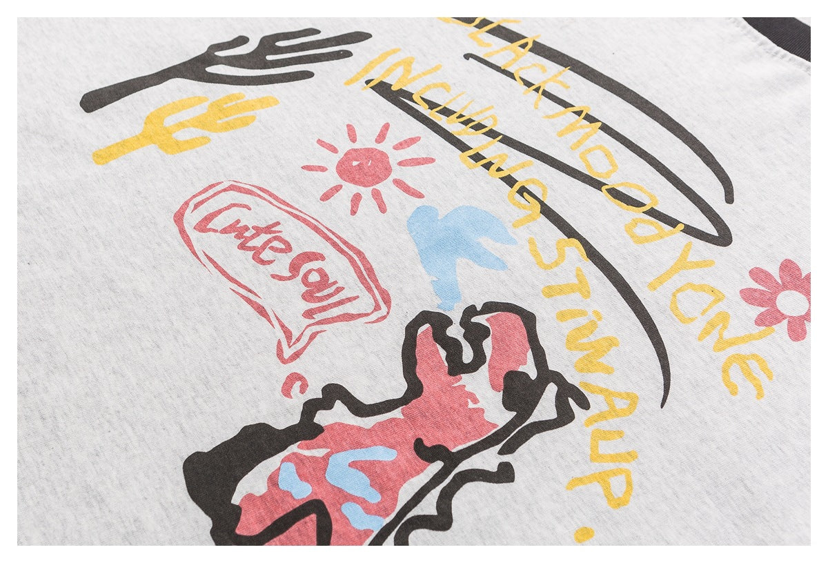 Close-up of a light gray shirt's colorful graphic print, including hand shapes, a sun, and English lettering.