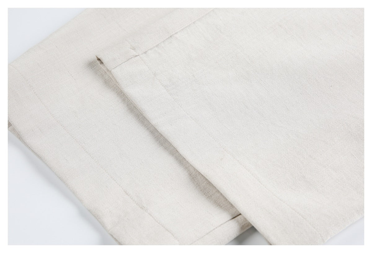 Close-up of a light beige trouser leg hem and stitching on a white background.