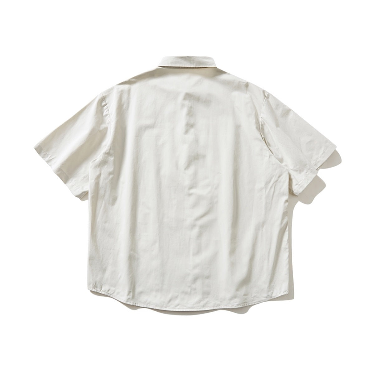 Back view of an ivory short-sleeve button-up shirt with a pointed collar and curved hem.