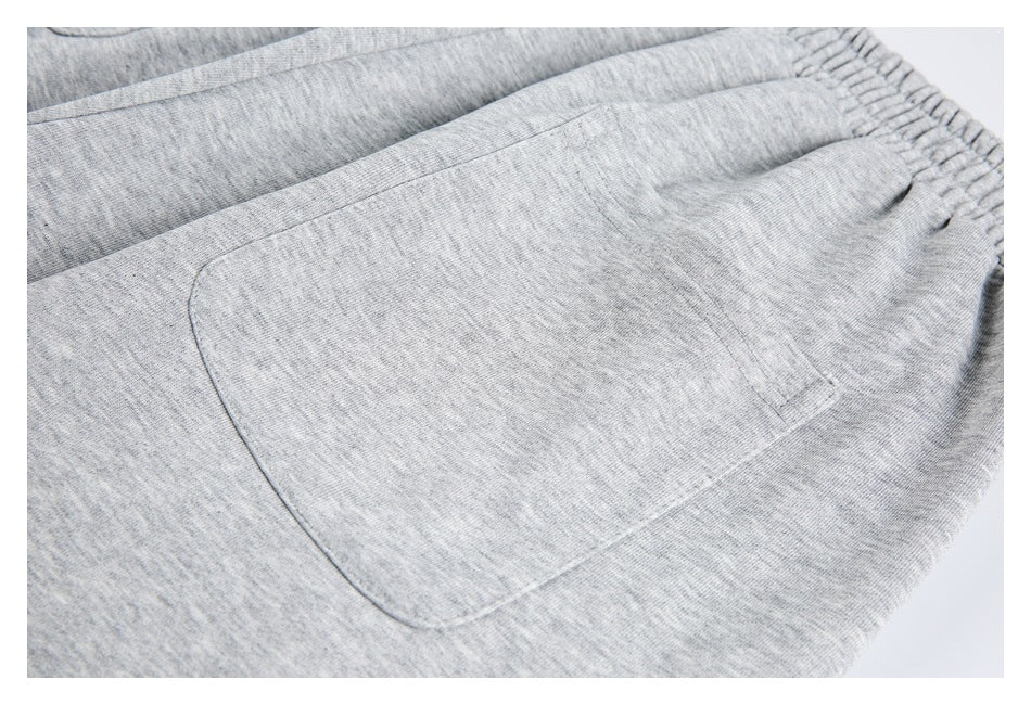 Close-up of a light gray garment showing a stitched patch pocket and gathered elastic waistband.