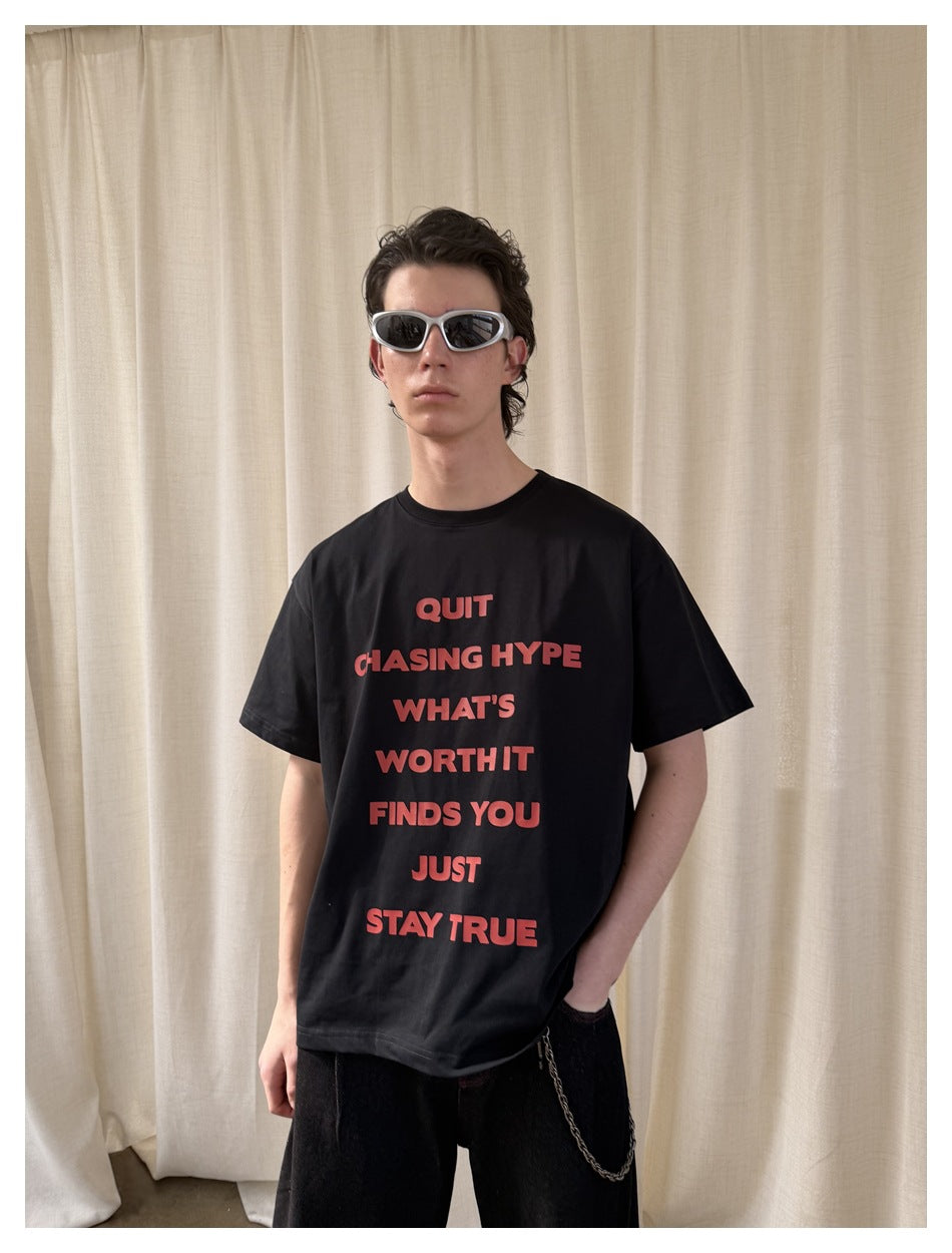 Front view of a model in a black T-shirt with a red text graphic and black shorts.
