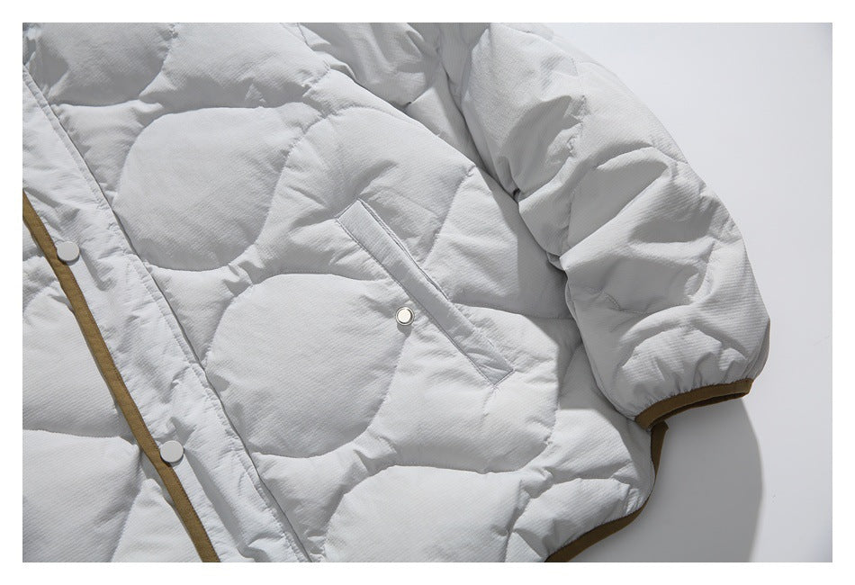 Close view of a light gray quilted jacket sleeve, angled snap pocket, and brown edging.