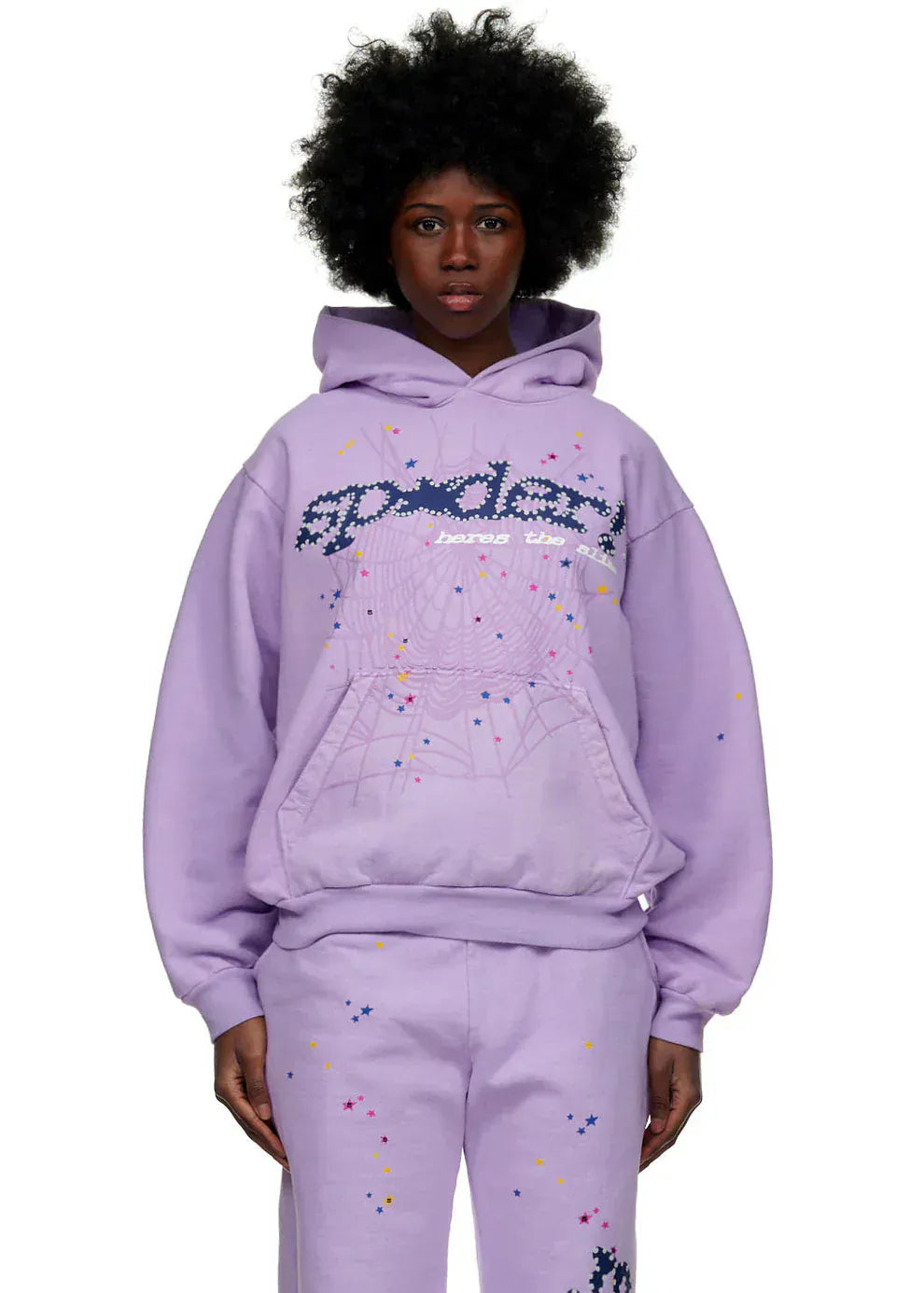 A person wears the Sp5der “Hares the Slime” Hoodie in lavender purple, a 440GSM heavyweight fleece pullover with a spider-web design and streetwear-inspired graphics, paired with matching splatter pants.