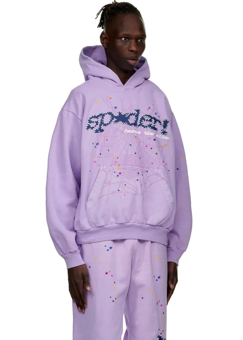 Wearing the Sp5der “Hares the Slime” Hoodie in lavender purple, a heavyweight 440GSM streetwear pullover with spider-web designs, a person stands against a plain white background.