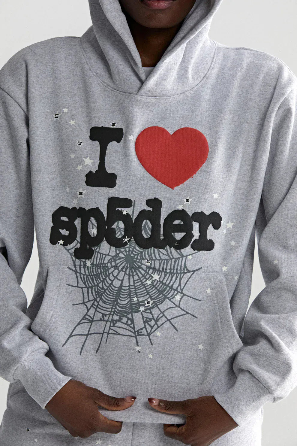 A person wearing the Sp5der “I Love Sp5der” Hoodie in grey, a 440GSM heavyweight oversized streetwear pullover with "I ♥ sp5der" and spiderweb graphic, embodying standout Y2K fashion.