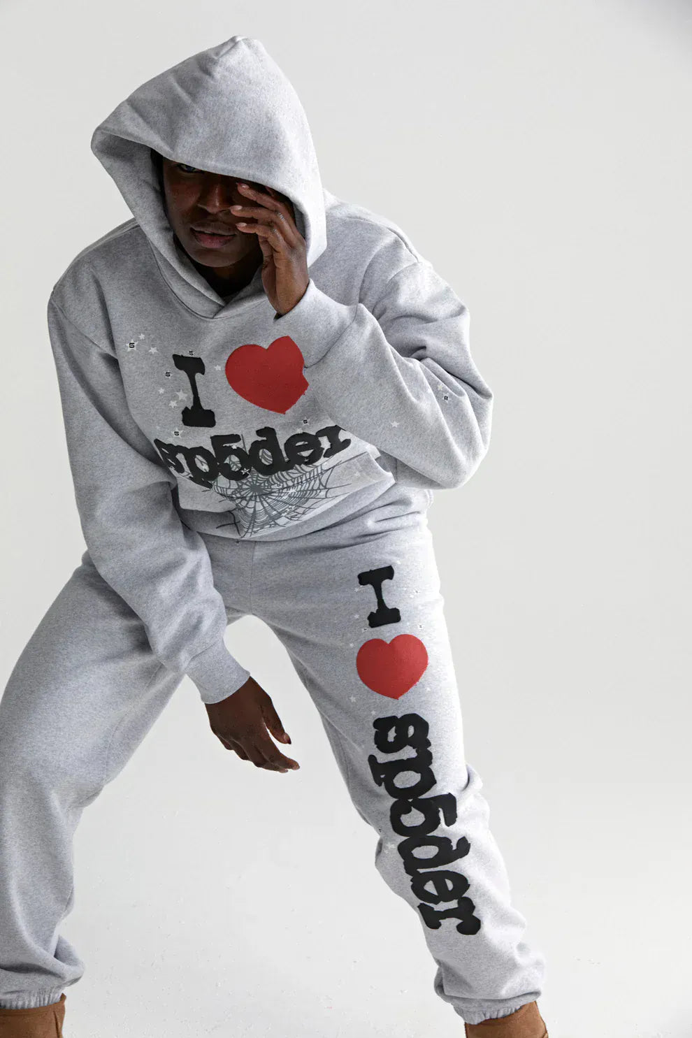 Wearing the Sp5der “I Love Sp5der” Hoodie – Grey 440GSM Heavyweight Oversized Streetwear Pullover, a person poses against a plain background, capturing the bold Y2K streetwear style with signature I ❤️ SP5DER logos.