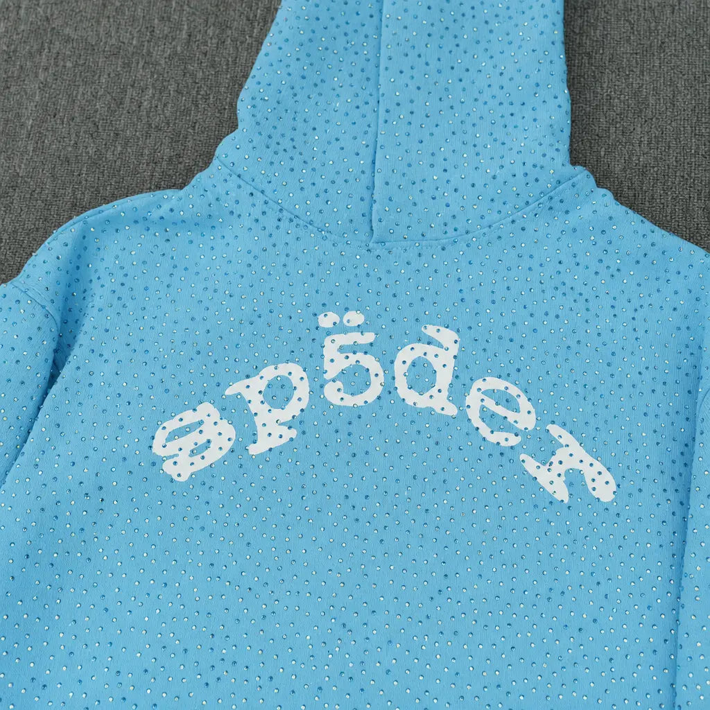 The Sp5der Baby Blue Rhinestone All-Over Arch Logo Hoodie features sparkling silver rhinestones and a bold white "sp5der" text across the back, making it a standout streetwear piece ideal for modern style.