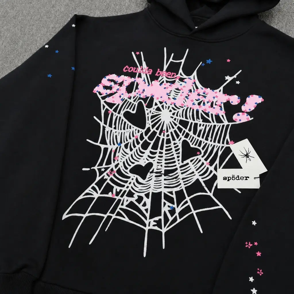 The Sp5der Black Hoodie Pink Spiderweb Graphic Streetwear features a bold white spider web with heart shapes, pink "couldve been Spiderr!" text, and two playing cards with a spider graphic and "sp8der" on one sleeve.