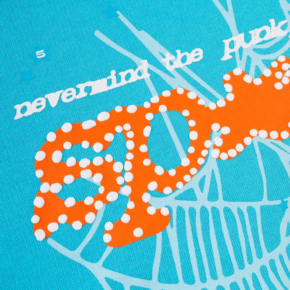 A close-up of a Sp5der “Nevermind the Spider” Hoodie – Sky Blue 440GSM shows a blue and orange graphic with "SPOT" in dots and “never mind the Purpl” in white, crafted from heavyweight premium cotton fleece.
