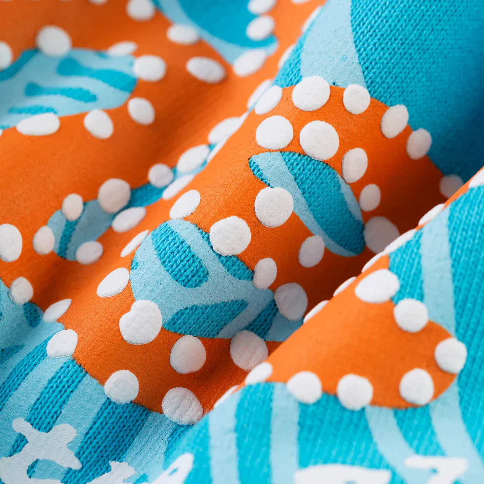 Close-up of premium cotton fleece with orange, blue, and white abstract polka-dot pattern and textured folds—ideal for crafting the Sp5der “Nevermind the Spider” Hoodie – Sky Blue 440GSM Heavyweight Streetwear Pullover.