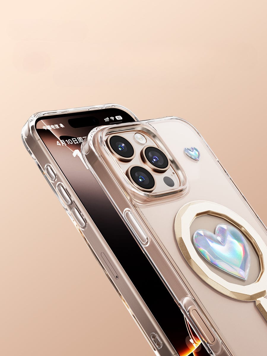 Two iPhone 16 Pro Max smartphones with crystal-clear cases, one highlighting the display screen and the other featuring a multi-camera setup enhanced by AI Precision Button Cutouts, along with a heart-shaped decorative accessory.