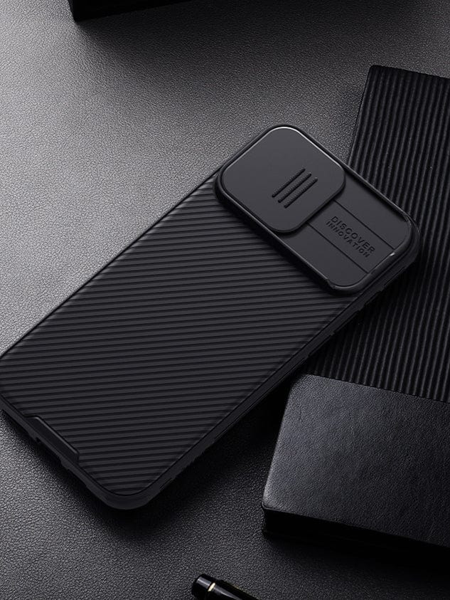 An iPhone 16 Pro Max Camera Slider Case, offering anti-scratch, shockproof, and slim-fit protection in black with dual-layer design and a sliding lens cover, is placed on a dark textured surface next to a notebook and a pen.